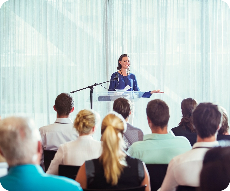 Speaker presenting to an audience at conference.